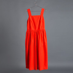 red fashionable dress hanging on a hanger on a gray background, concept of shopping and fashion