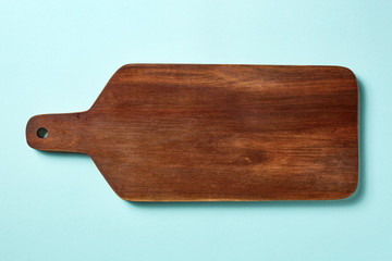 Wooden cutting board on blue background, from above