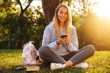 Portrait of a cute young girl sitting on a grass at the park