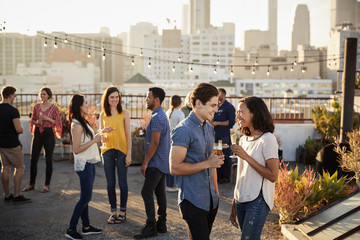 Friends Gathered On Rooftop Terrace For Party With City Skyline In Background