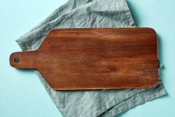 Wooden cutting board on blue background, from above