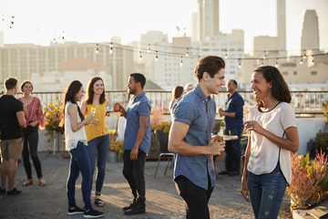 Friends Gathered On Rooftop Terrace For Party With City Skyline In Background