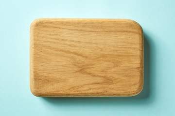 Wooden cutting board on blue background, from above