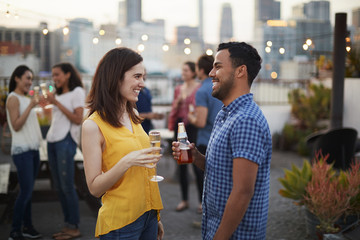 Friends Gathered On Rooftop Terrace For Party With City Skyline In Background