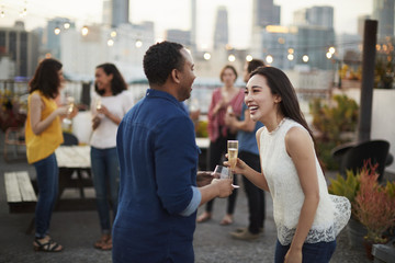 Friends Gathered On Rooftop Terrace For Party With City Skyline In Background