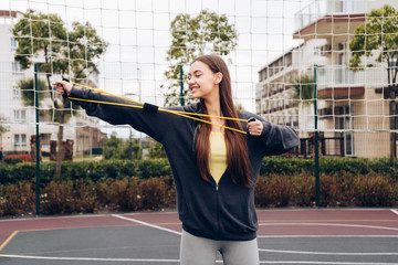 active long-haired girl doing exercises for the muscles of the hands on the sports field