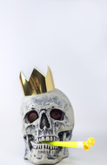 Halloween human gray skull imitation with festive pipe in mouth and golden crown on head. Decorating for holiday Halloween. The concept of eternal holiday.