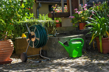 garten mit Brunnen und Gießkanne sowie Wassershclauch zum gießen