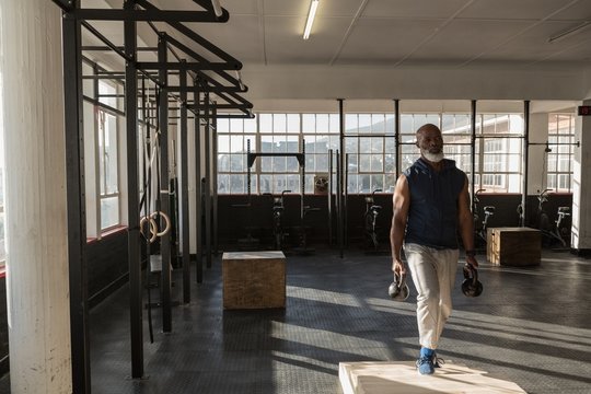 Senior man exercising with kettlebells in gym