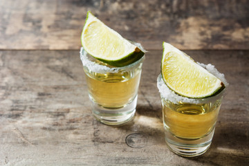 Mexican Gold tequila with lime and salt on wooden table