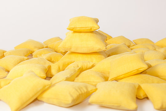 Yellow Pillows Stacked In A Pile On A Light Background