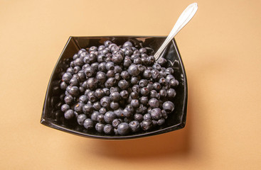blueberries in a glass plate on an orange background