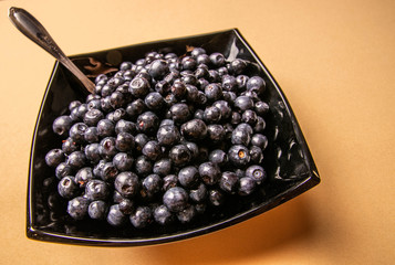 blueberries in a glass plate on an orange background