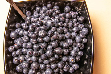 blueberries in a glass plate on an orange background.