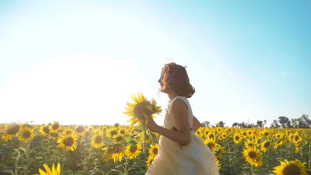 Happy little girl running happy free across the field with sunflowers. slow motion video. smelling big sunflower on summer field lifestyle. Delight of a pleasant smell. Summer holiday. concept