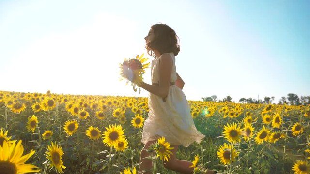 Happy little girl running happy free across the field with lifestyle sunflowers. slow motion video . smelling big sunflower on summer field. Delight of a pleasant smell. Summer holiday. concept