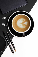 Set of black identity elements and cup of coffee on black and white paper background. Branding mockup