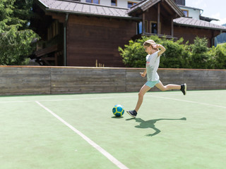 Ein 9 jähriges Mädchen trainiert ihre Schußtechnik mit einem Fußball uf dem Fußballplatz
