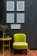 Modern yellow fabric chair and white wooden picture frame on black wall interior decoration