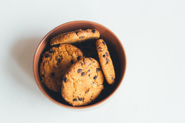 Chocolate cookies in a brown bowl on a white background, top view