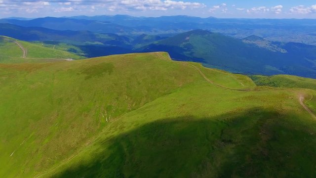 Aerial shot of colorful ridges with arty clouds in the Carpathians in summer