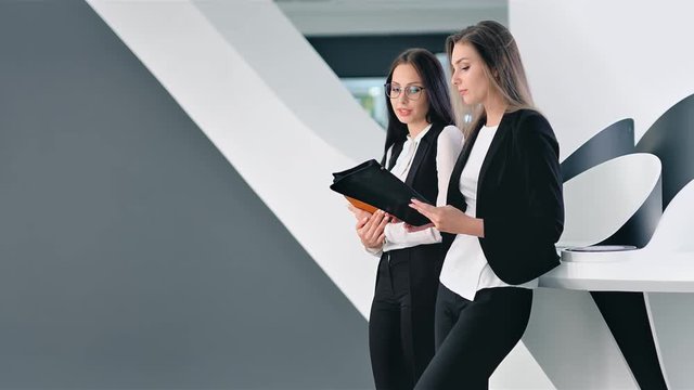 Two attractive young businesswoman having informal team meeting at futuristic office