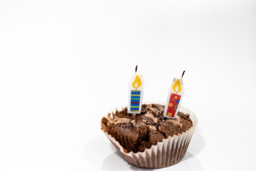 Two candles party on a chocolate cupcake isolated on a white background