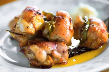 Chicken roll with bacon, pepper and onion on needle.