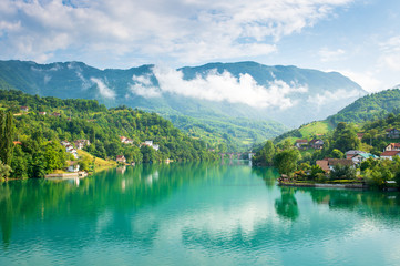 Fototapeta na wymiar Turquoise lake and mountains with clouds
