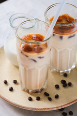 Iced coffee in a tall glass served on a plate on a white background.