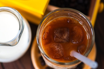 Iced coffee in a tall glass on a wooden background. Top view.