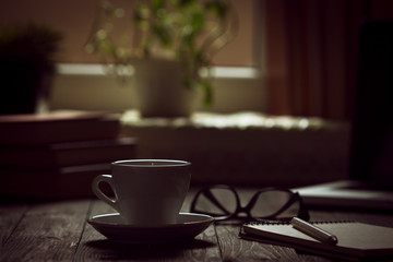 A cup of coffee in the workplace on a wooden table.