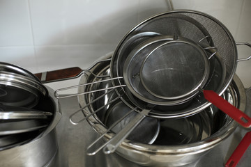 set of metal black pans and pots and colander on kitchen