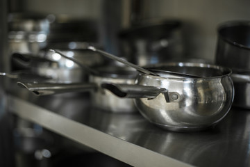 set of metal black pans and pots and colander on kitchen