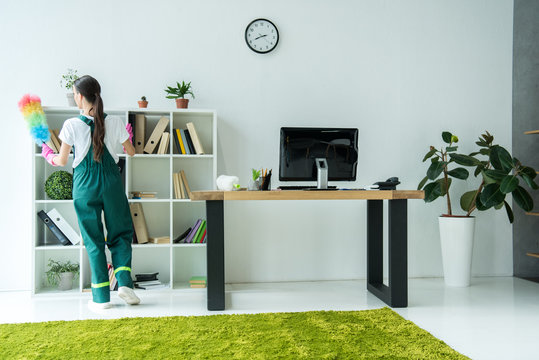 Back View Of Young Cleaner Holding Duster And Cleaning Modern Office