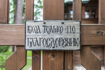 The plate on the wooden fence doorway with the inscription on Russian meaning literally 