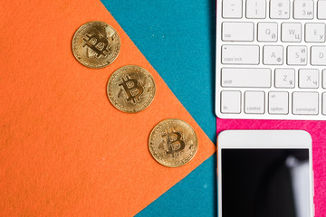 Golden bitcoins on a top, and smart phone and laptop.