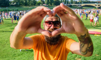 Man bearded hipster in front of crowd people show heart gesture riverside background. Hipster happy...