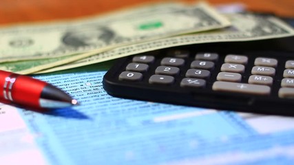 Concept of paying annually taxes; tax document, dollar paper money, calculator and a pen.