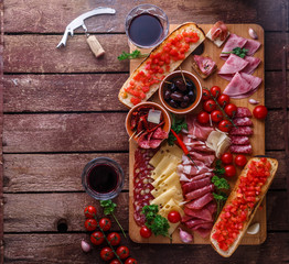 Meat and cheese appetizer set for red wine on rustic background, flatlay, copy space.