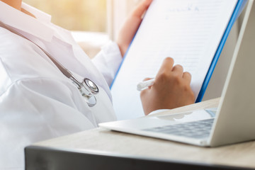 Fototapeta premium Healthcare medical hospital concept : Doctor intern using tablet computer with gown suite wearing Stethoscope on neck for seaching information treating patients in clinic