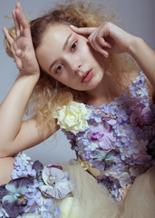 Studio portrait of blooming gorgeous lady in dress of flowers. Tired mood. Fashion concept