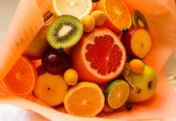 Bouquet of flowers and fresh citrus fruits wrapped in coarse paper in hands