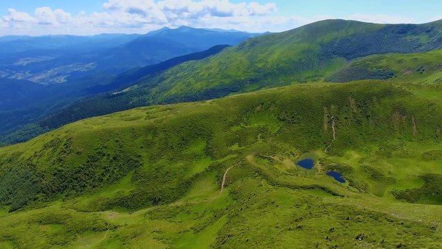 Aerial shot of an oval mountain and two small ponds in the Carpathians in summer