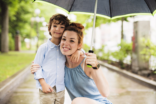 Mother And Child On A Rainy Day In A Park With Umbrella