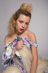 Beautiful young woman is dressed in a avant garde long dress from flowers. Fashion Studio Portrait