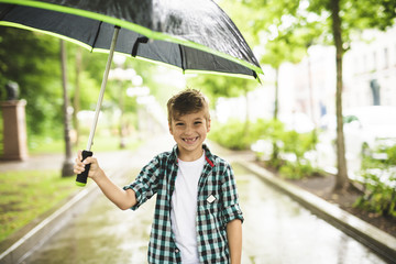 Cute boy, walking in a park on a rainy day