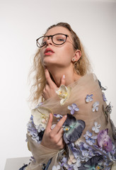 Beautiful young woman is dressed in a avant garde long dress from flowers. Fashion Studio Portrait