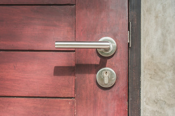 Close up door handle on closed brown wooden door. (Selective focus)