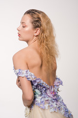 Studio portrait of blooming gorgeous lady in dress of flowers. Fashion concept